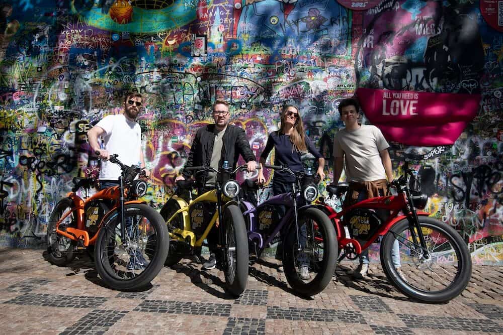 Four riders with colorful café-racer e-bikes on Old Town Square
